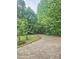 A concrete driveway winds through lush trees to a charming home at 4855 West Price Rd, Sugar Hill, GA 30518
