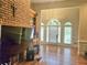 Open living room with hardwood floors, brick fireplace, and large windows bringing in natural light at 4855 West Price Rd, Sugar Hill, GA 30518
