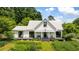 Charming farmhouse with a metal roof and covered porch, nestled among lush greenery at 10975 Hutcheson Ferry Rd, Chattahoochee Hills, GA 30268