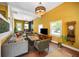 Spacious living room with vibrant yellow walls, fireplace, comfortable seating, and natural light at 10975 Hutcheson Ferry Rd, Chattahoochee Hills, GA 30268