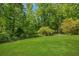 Large grassy backyard featuring lush green trees and an enclosing fence, ideal for outdoor activities at 1380 Heritage Glen Dr, Marietta, GA 30068