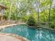 Tranquil backyard pool surrounded by lush greenery, adjacent to a spacious deck for lounging at 3809 Cotswold Sw Dr, Lilburn, GA 30047