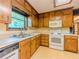 Cozy kitchen featuring wood cabinets, a stainless steel sink, and white appliances, offering a functional cooking space at 3809 Cotswold Sw Dr, Lilburn, GA 30047
