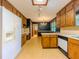 Spacious kitchen with wood cabinetry, white appliances, adjacent to a dining area with a chandelier at 3809 Cotswold Sw Dr, Lilburn, GA 30047