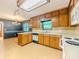 Traditional kitchen with wood cabinetry, white appliances, and a large dining area with a chandelier at 3809 Cotswold Sw Dr, Lilburn, GA 30047