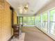 Bright sunroom featuring large windows, brick walls, ceiling fan, and vintage wood-burning stove at 3809 Cotswold Sw Dr, Lilburn, GA 30047