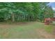Grassy backyard with stairs leading to a deck and a natural landscape at 1558 Ember Oaks Cir, Powder Springs, GA 30127