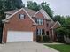 Beautiful two-story brick house featuring an attached garage, manicured shrubs and a long driveway at 1558 Ember Oaks Cir, Powder Springs, GA 30127