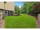 Beautiful backyard with green lawn, tall trees, manicured landscaping, and a screened-in porch at 1348 Bridgemill Ave, Canton, GA 30114