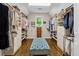 Spacious walk-in closet with custom shelving, drawers, wood flooring and large blue ottoman for optimal storage at 1348 Bridgemill Ave, Canton, GA 30114