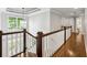 Hallway with hardwood floors, modern chandelier, and white railings overlooking staircase at 1348 Bridgemill Ave, Canton, GA 30114