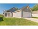 Side view of a gray home featuring an attached garage, complemented by a lush green lawn and serene surroundings at 363 Chadwick Cmn, Stockbridge, GA 30281