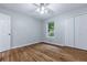Bright bedroom featuring hardwood floors, a ceiling fan and closet with window view to trees outside at 288 Shire Way, Lawrenceville, GA 30044
