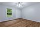 Bright bedroom featuring hardwood floors, a ceiling fan and closet with window view to trees outside at 288 Shire Way, Lawrenceville, GA 30044