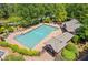 Aerial view of a community pool with lounge chairs, mature trees, and a brick pool house at 5791 Epping Ct, Douglasville, GA 30135