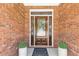 Close up of front door with glass detailing, planters, and brick surround at 5791 Epping Ct, Douglasville, GA 30135