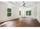 Spacious bedroom with hardwood floors, tray ceiling with fan, and windows overlooking trees at 10350 Alvin Rd, Johns Creek, GA 30022