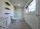 Modern bathroom featuring floating shelves, large window, shower with a glass door and grey tiled floors at 2400 Glenrock Dr, Decatur, GA 30032