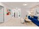 Open bonus room with neutral carpet, colorful artwork, and a stylish blue velvet sofa at 520 Amethyst Way, Stockbridge, GA 30281