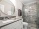Modern bathroom features a stone tiled shower, a large round mirror, and white cabinets at 8957 Old Southwick Pass, Johns Creek, GA 30022