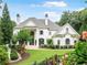 Stunning white brick home with lush landscaping, elegant architectural details, and a well-manicured lawn at 8957 Old Southwick Pass, Johns Creek, GA 30022