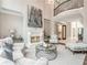 Bright and airy living room featuring a fireplace, elegant furnishings, and a view of the upper-level balcony at 8957 Old Southwick Pass, Johns Creek, GA 30022