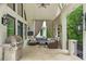Spacious outdoor living area with grill, lounge seating, curtains, and neutral brick flooring at 8957 Old Southwick Pass, Johns Creek, GA 30022
