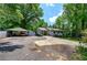 Single-story house with a driveway leading to a carport, surrounded by lush trees and a well-maintained lawn at 1095 Dallas Nebo Rd, Dallas, GA 30157