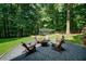 Secluded backyard fire pit with wooden chairs surrounded by lush trees and a trampoline at 118 Whitestone Dr, Mcdonough, GA 30253