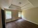 Bedroom featuring neutral walls, wood floors, and tray ceilings with windows for natural light at 257 Juliet Dr, Hampton, GA 30228