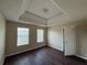 Bedroom with tray ceilings, wood floors, neutral walls, white trim, and large windows for natural light at 257 Juliet Dr, Hampton, GA 30228