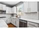 Well-lit kitchen with white cabinetry, stainless steel dishwasher, and granite countertops by window at 4092 Grand Park Dr, Suwanee, GA 30024