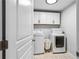 Laundry room with white washer and dryer, storage cabinets, and a neutral rug at 4092 Grand Park Dr, Suwanee, GA 30024