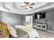 Main bedroom with tray ceilings, decorative console, a TV and neutral carpeting at 4092 Grand Park Dr, Suwanee, GA 30024