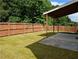 A spacious backyard featuring a covered patio, green lawn, and wooden fence at 4605 Fourth Rail Ln, Cumming, GA 30040