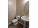 A half bathroom featuring a pedestal sink, toilet, and round mirror at 4605 Fourth Rail Ln, Cumming, GA 30040