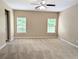 A spacious bedroom featuring neutral walls, carpeting, ceiling fan, and natural light at 4605 Fourth Rail Ln, Cumming, GA 30040