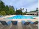 A beautiful community pool is surrounded by tall green trees and plenty of lounge chairs at 4605 Fourth Rail Ln, Cumming, GA 30040