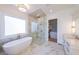 Bright bathroom featuring a freestanding tub, marble floors, glass-enclosed shower, and modern fixtures at 2837 Darlington Run, Duluth, GA 30097