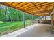 View of the covered patio with exposed wood ceiling and large grassy area in the backyard at 4826 Dean Sw Ln, Lilburn, GA 30047
