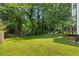 Large backyard with a grass lawn surrounded by mature trees at 5250 Forest Downs Ln, Atlanta, GA 30349