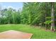 Backyard with a grassy field, bordered by a lush green treeline at 130 Bingley Ct, Covington, GA 30016