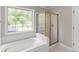 Bright bathroom showcasing a bathtub with a large window and a glass-enclosed shower at 30 Stonewall Dr, Covington, GA 30016