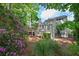 Picturesque back exterior with a large deck, blooming flowers, and beautiful natural surroundings at 3004 High Vista Walk, Woodstock, GA 30189