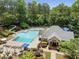 Aerial view of a community pool with a slide, lounge chairs, and manicured landscaping surrounded by lush trees at 3004 High Vista Walk, Woodstock, GA 30189