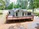 Rear exterior view featuring a large deck, a light-green facade, and black-framed windows at 7619 Campground Rd, Cumming, GA 30040
