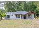 Charming single-story home with a covered front porch, neutral siding, and dark-trimmed windows surrounded by mature trees at 7619 Campground Rd, Cumming, GA 30040
