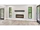 Modern living room features a sleek fireplace, wood-look floors, and black framed windows with natural light at 7619 Campground Rd, Cumming, GA 30040