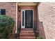Close-up of the elegant front door, boasting a decorative glass panel and brick surroundings at 1887 Chamdun Pl, Brookhaven, GA 30341
