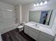 Bathroom featuring dark laminate floors, white vanity, and a tub-shower at 7791 Sudbury Cir, Covington, GA 30014